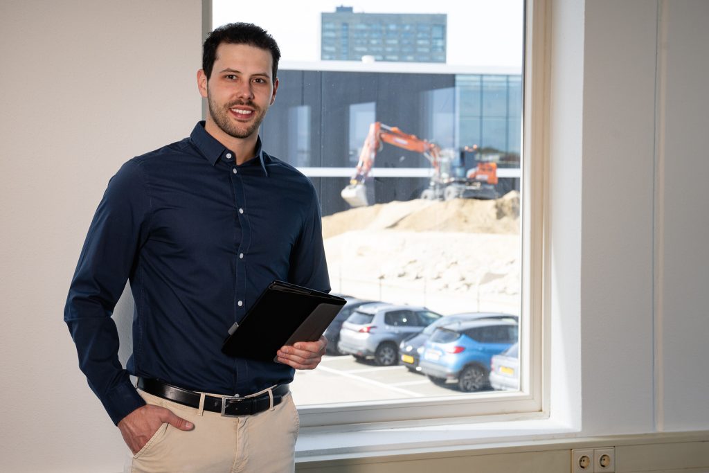 Man met tablet voor bouwplaats raam.