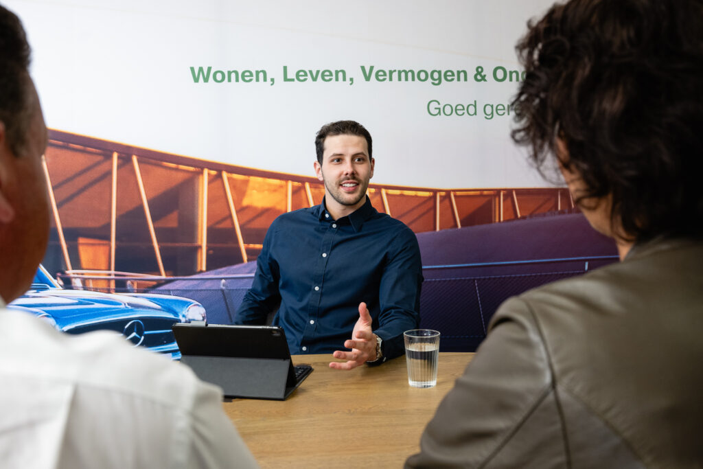 Man in gesprek bij vergadering met anderen.