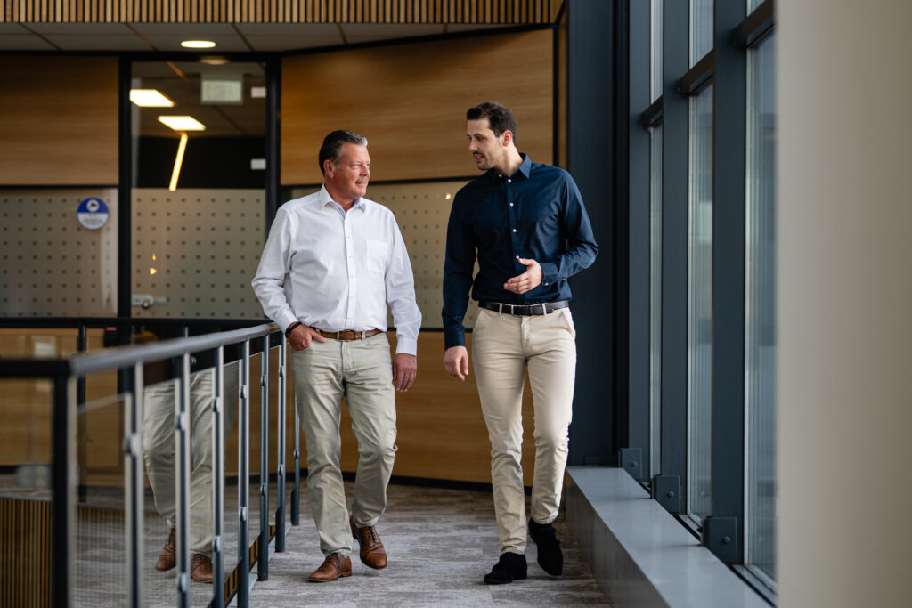 Twee mannen praten en lopen door kantoor.