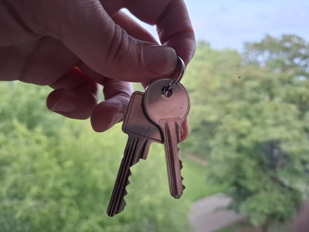 Hand houdt sleutels vast voor groen landschap.